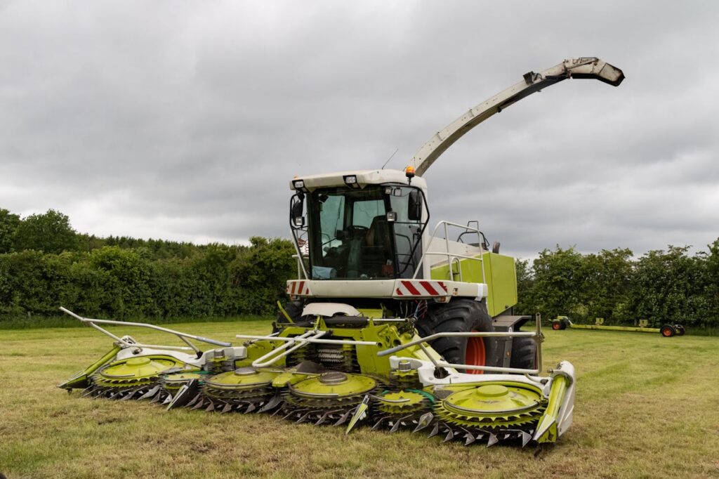 Forage harvester machine parked in a rural field, ready for crop harvesting.